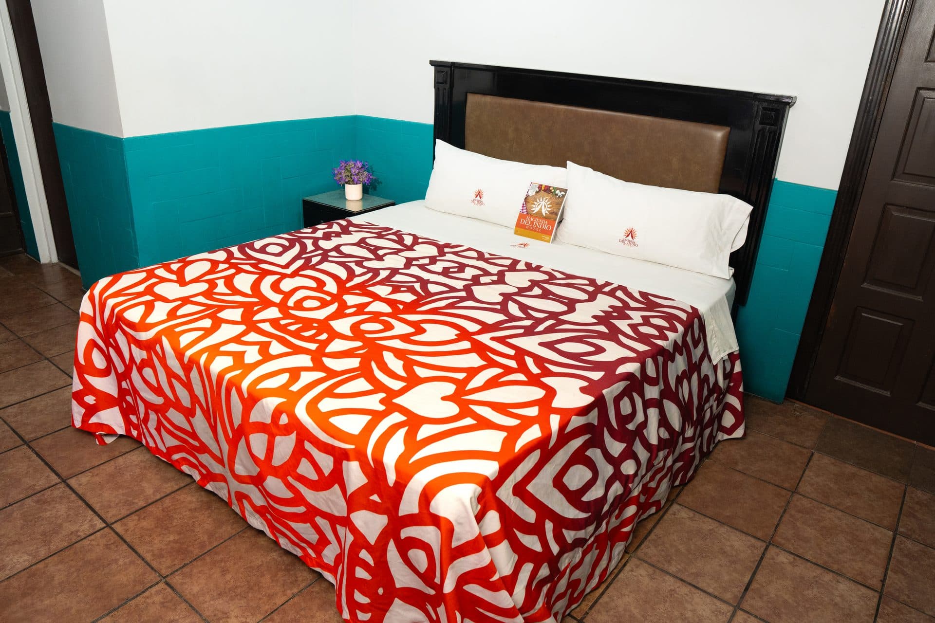 Vista frontal de la cama con cabecera de madera y almohadas con logotipo