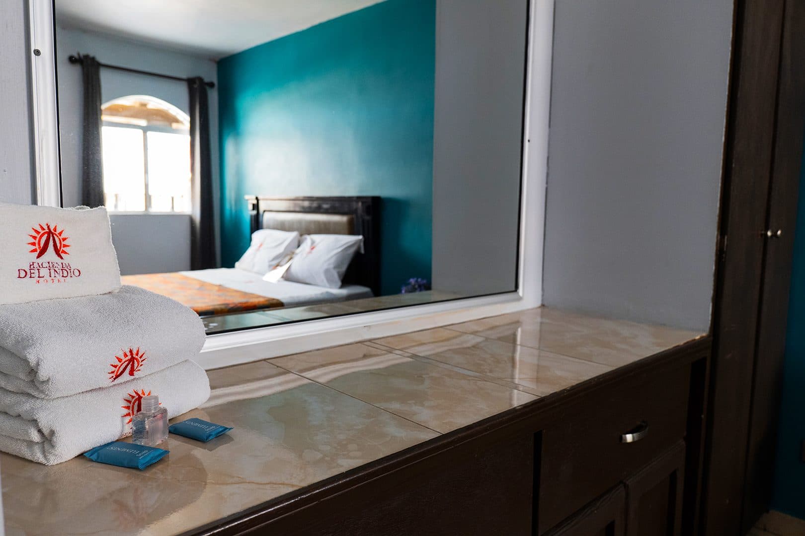 Toallas bordadas con el logotipo y cama de la habitación al fondo